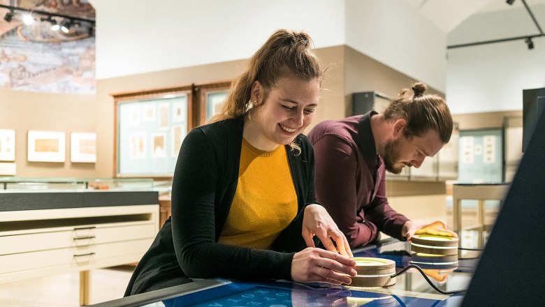 Papyrusmuseum der Österreichischen Nationalbibliothek, © Pichler Zwei Personen interagieren mit einem interaktiven Display im Papyrusmuseum.