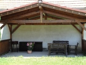 Pension Steindl, © Familie Steindl Überdachte Terrasse mit Holzbänken und einem Blumentopf.
