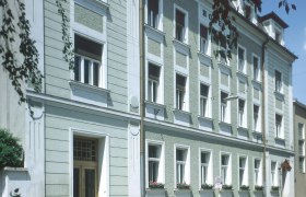 Aussenansicht, © Zauza Außenansicht eines mehrstöckigen Gebäudes mit grüner Fassade und weißen Fensterrahmen.