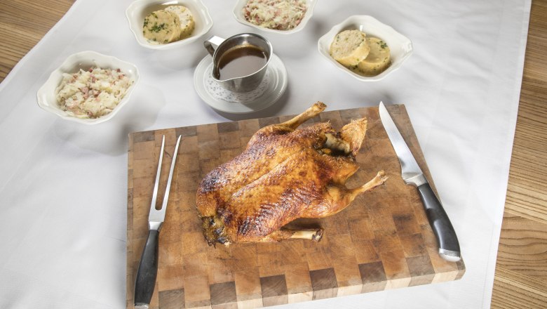 Specialty: Farm duck, © Niederösterreich Werbung/Kurt Pinter Baked duck on a wooden board with side dishes and sauce.