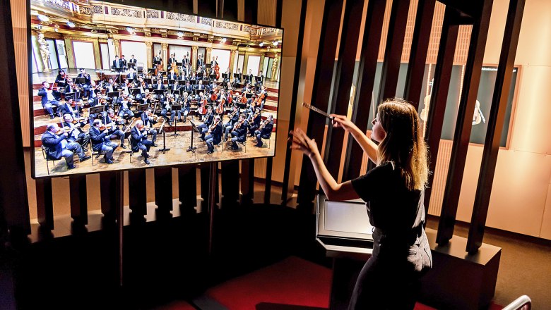 Haus der Musik, © Hanna Pribitzer Person dirigiert virtuelles Orchester auf Bildschirm im Haus der Musik.
