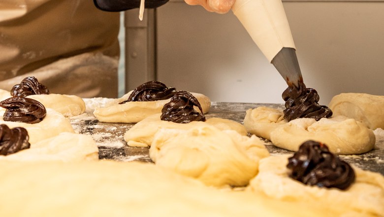 Elvira Smetana filling the yeast dumplings, © Niederösterreich Werbung/Kurt Pinter Woman filling yeast dumplings from a piping bag.
