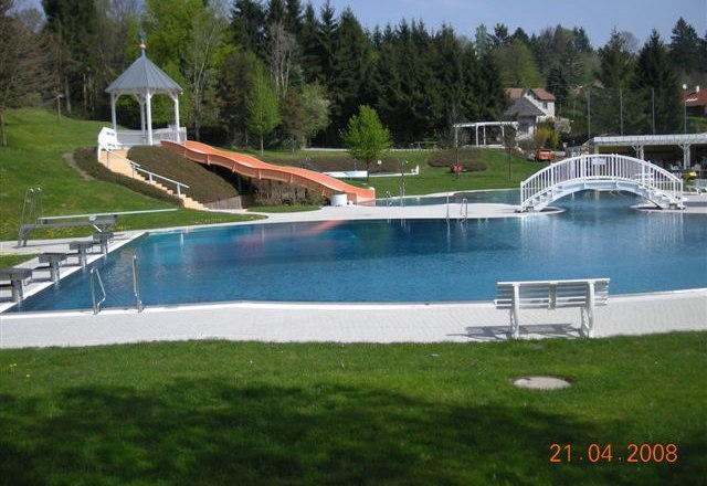 Erlebnisbad Eichgraben, © Gemeinde Eichgraben Freibad mit Rutsche, Brücke und Pavillon im Hintergrund.