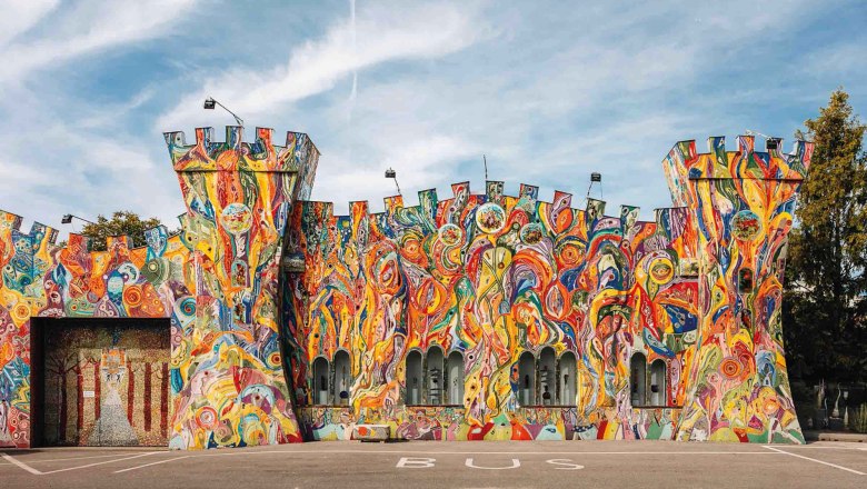 Glasmuseum "Die gläserne Burg", © Kuchlerhaus GmbH Bunt bemalte Fassade eines Gebäudes in Form einer Burg mit Türmen.
