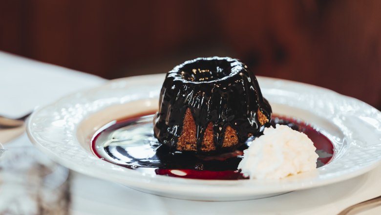 "Gugginger" with chocolate sauce and whipped cream, © Niederösterreich Werbung/David Schreiber A Gugelhupf with chocolate sauce and whipped cream on a plate.