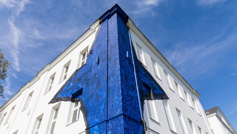Museum Gugging, © NÖ Museum Betriebs GmbH/Ludwig Schedl Gebäude mit blauer Wandkunst an der Ecke, vor blauem Himmel.
