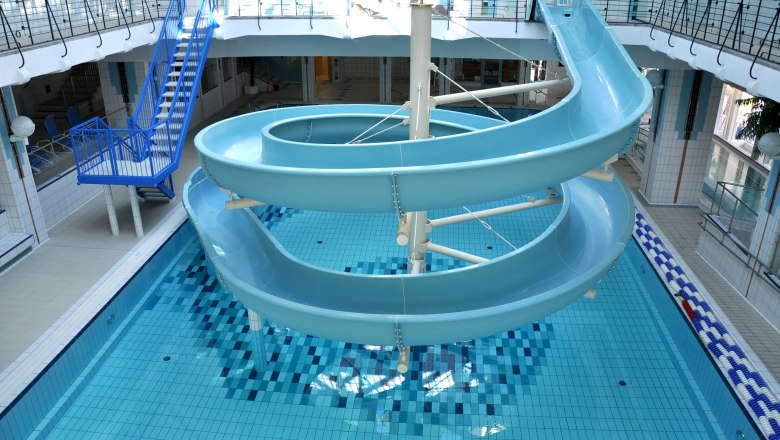 Indoor swimming pool, © Freizeitzentrum Stadtbad Mödling Interior view of an indoor pool with blue water slide and swimming pool.