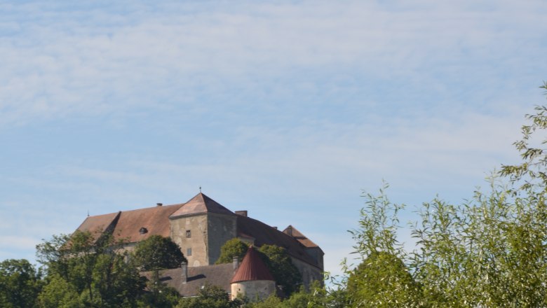 Burg Neulengbach, © Stadtgemeinde Neulengbach Burg Neulengbach auf einem bewaldeten Hügel unter blauem Himmel.