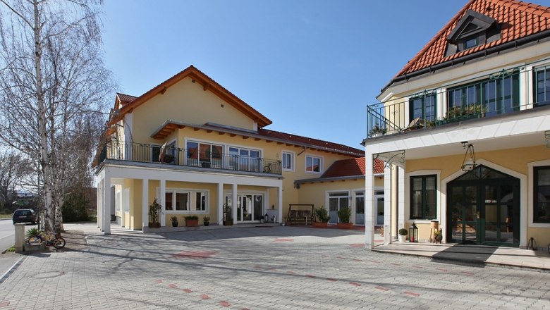 Winzerhof Aussenansicht, © Winzerhof Achau Außenansicht eines gelben Winzerhofs mit roten Dächern und gepflastertem Hof.