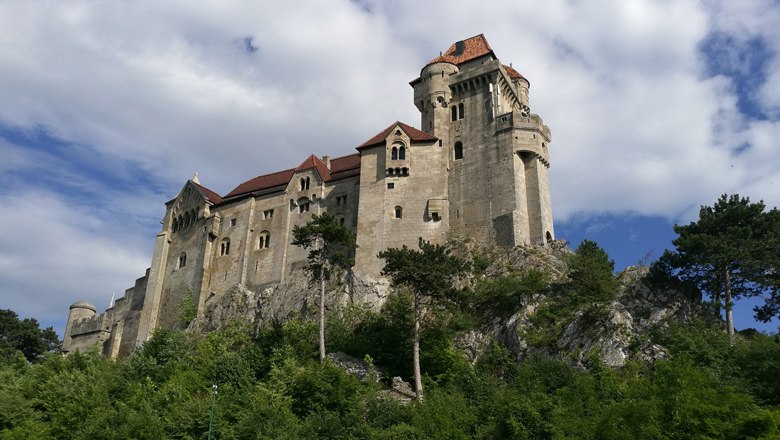 Liechtenstein Castle, © Burg Liechtenstein Betriebs GmbH Liechtenstein Castle on a hill with trees and a blue sky.