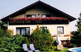 Haus, © Haus Alpenland Bad Vöslau Zweistöckiges Haus mit Balkon, Gartenmöbeln und Pool im Vordergrund.