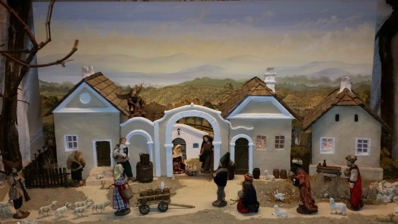 Weinviertler Krippe, © Krippenmuseum Vösendorf Weihnachtskrippe mit Figuren und Gebäuden in ländlicher Szenerie.
