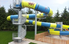 Large water slide, © Dagmar Ackerl Large water slide with blue and yellow tubes and spiral staircase.