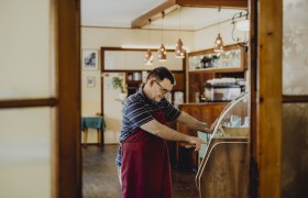 Gemütliche Stube mit Musikbox, © Niederösterreich Werbung/Sophie Menegaldo Ein Mann in einer gemütlichen Stube bedient eine Musikbox.
