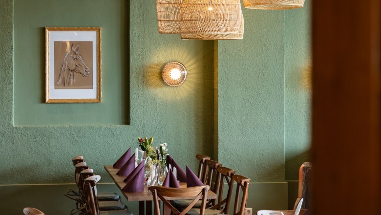 Tradition trifft Charme, © thefirstthought Gemütlicher Essbereich mit Holztisch, Stühlen und geflochtenen Lampen.