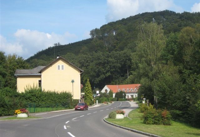 Wolfsgraben, © Wolfsgraben Ländliche Straße mit Häusern und bewaldetem Hügel im Hintergrund.