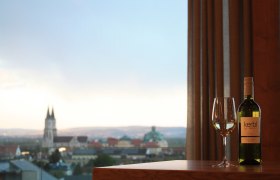 Aussicht Kerbl am Weinberg, © Leopold Kerbl Weinflasche und Glas vor Stadtpanorama mit Kirche.