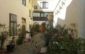 Hof im Sommer, © Norbert Stock Ein sonniger Innenhof mit Pflanzen und Sitzgelegenheiten.