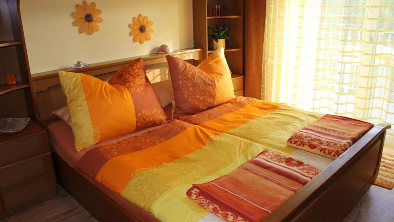 Zimmer Sonnenblume, © privat Gemütliches Schlafzimmer mit Sonnenblumen-Dekor und orange-gelber Bettwäsche.