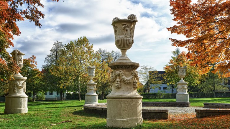 schlosspark-johann-ployer007_gross, © Johann Ployer Stone sculptures in an autumnal park with colorful foliage and blue sky.