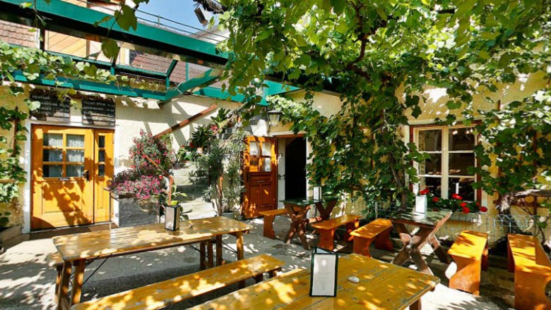 Inner courtyard, © Leeb Johannes A cozy courtyard with wooden benches and tables, surrounded by green vines and plants.