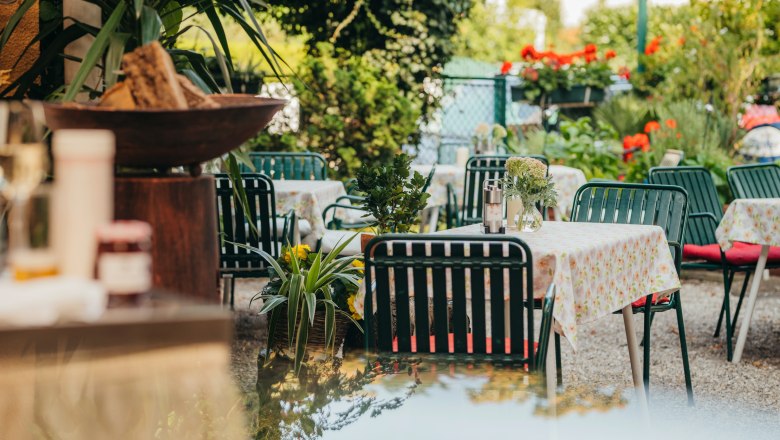 Idyllic guest garden, © Niederösterreich Werbung/Daniela Führer A cozy guest garden with tables and chairs, surrounded by plants and flowers.