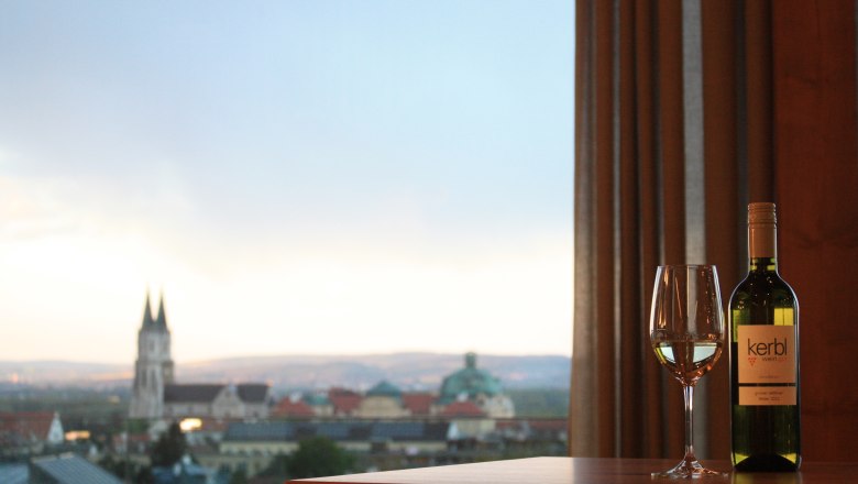 View Kerbl am Weinberg, © Leopold Kerbl Wine bottle and glass in front of city panorama with church.