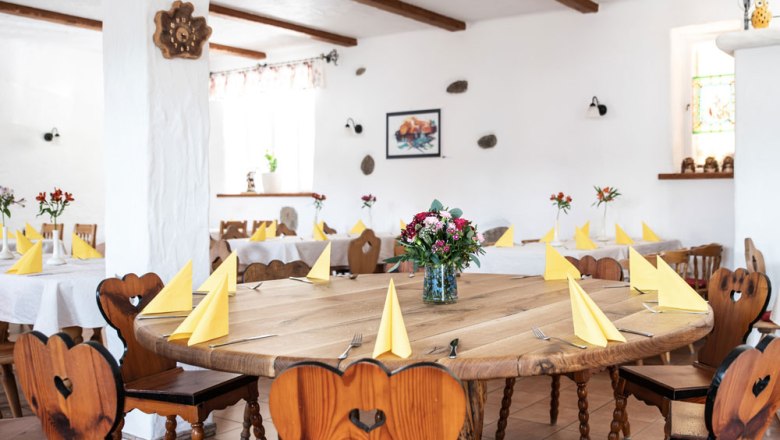 Parlor with regulars' music table, © Niederösterreich Werbung/Nadja Büchler A cozy room with wooden tables and chairs, yellow napkins and flower arrangements.