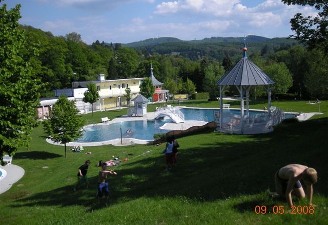 Badegäste, © Gemeinde Eichgraben Ein Freibad mit Badegästen auf einer Wiese und einem Pavillon im Hintergrund.