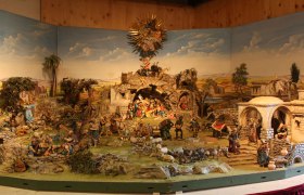 Alpine nativity scene with figures and landscape.