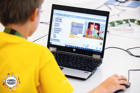 ein Bub von hinten zu sehen, der gerade an einem Laptop in Scratch ein Spiel programmiert