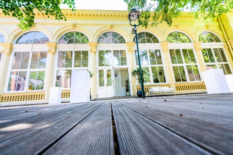 Außenansicht des Kursalon Mödling mit großen Fenstern und Holzboden.