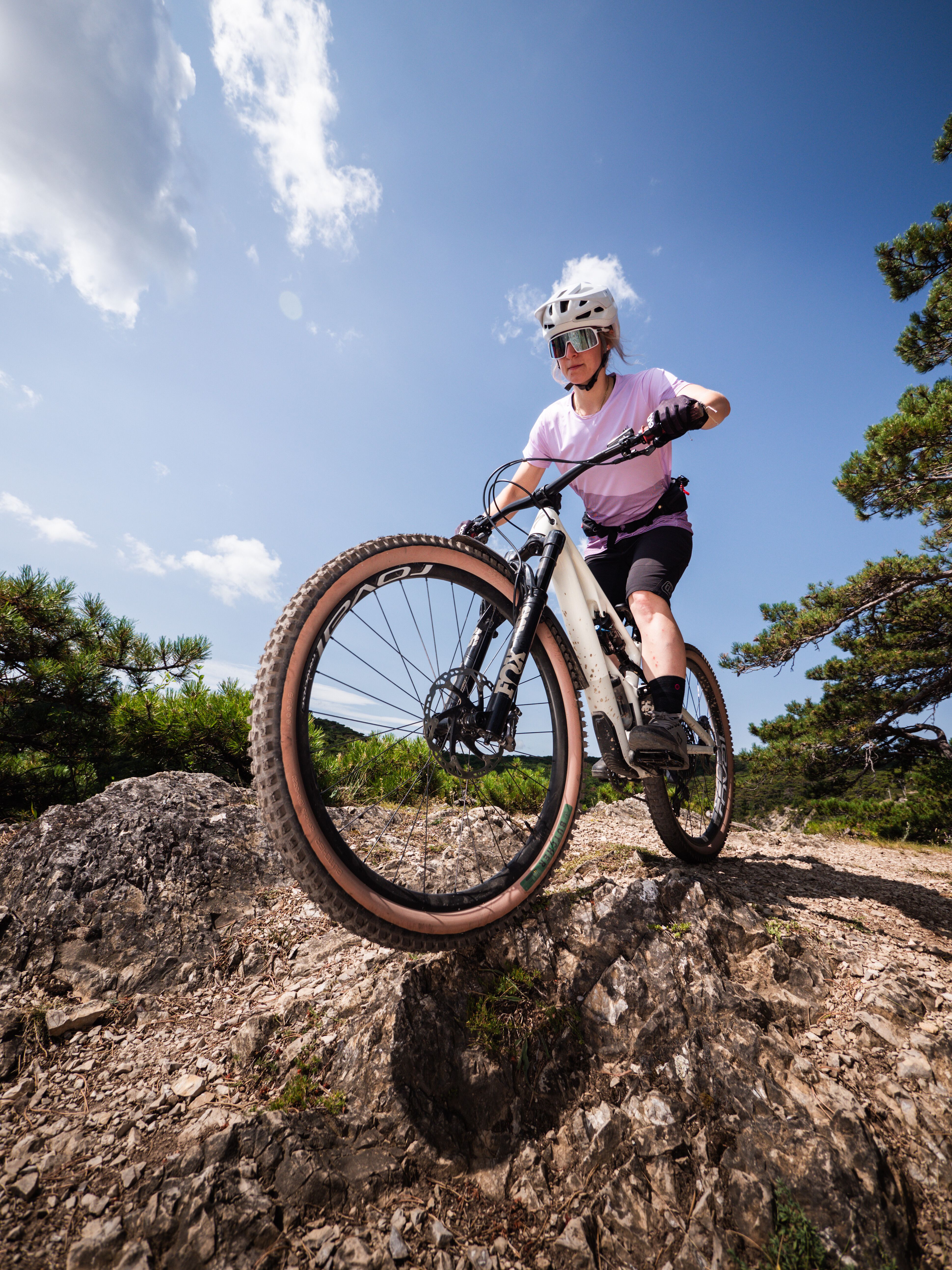 Ein Mountainbiker meistert mit Leichtigkeit die herausfordernde Strecke, während die Sonne am klaren Himmel strahlt. Umgeben von der üppigen Natur des Wienerwaldes, spürt man die Freiheit und den Adrenalinkick, die diese Region bietet. Der Anninger Trail lädt Abenteurer ein, die Schönheit der Landschaft zu entdecken.