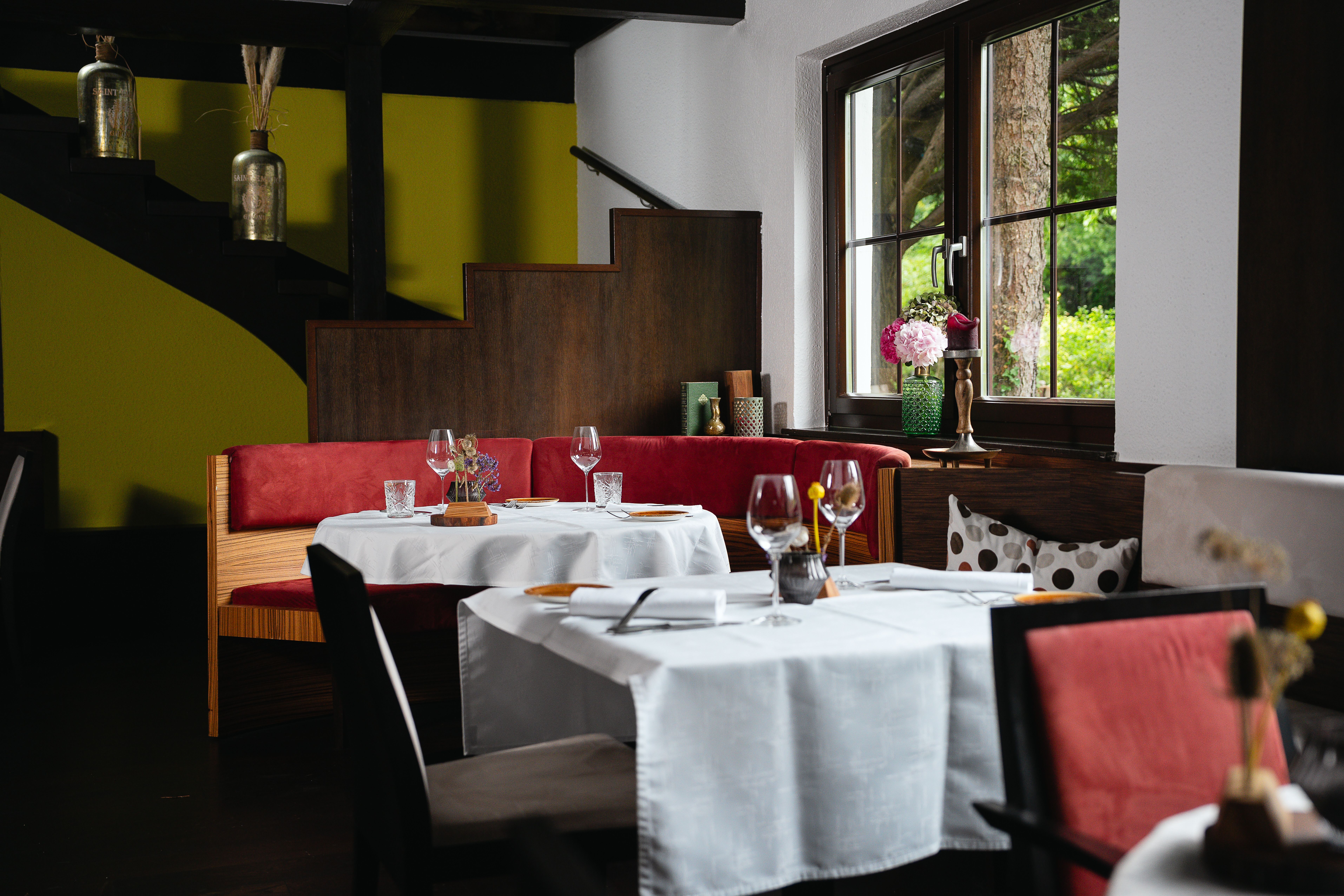 Stilvoll gedeckte Tische in einem elegant eingerichteten Restaurant mit roten Polstermöbeln.