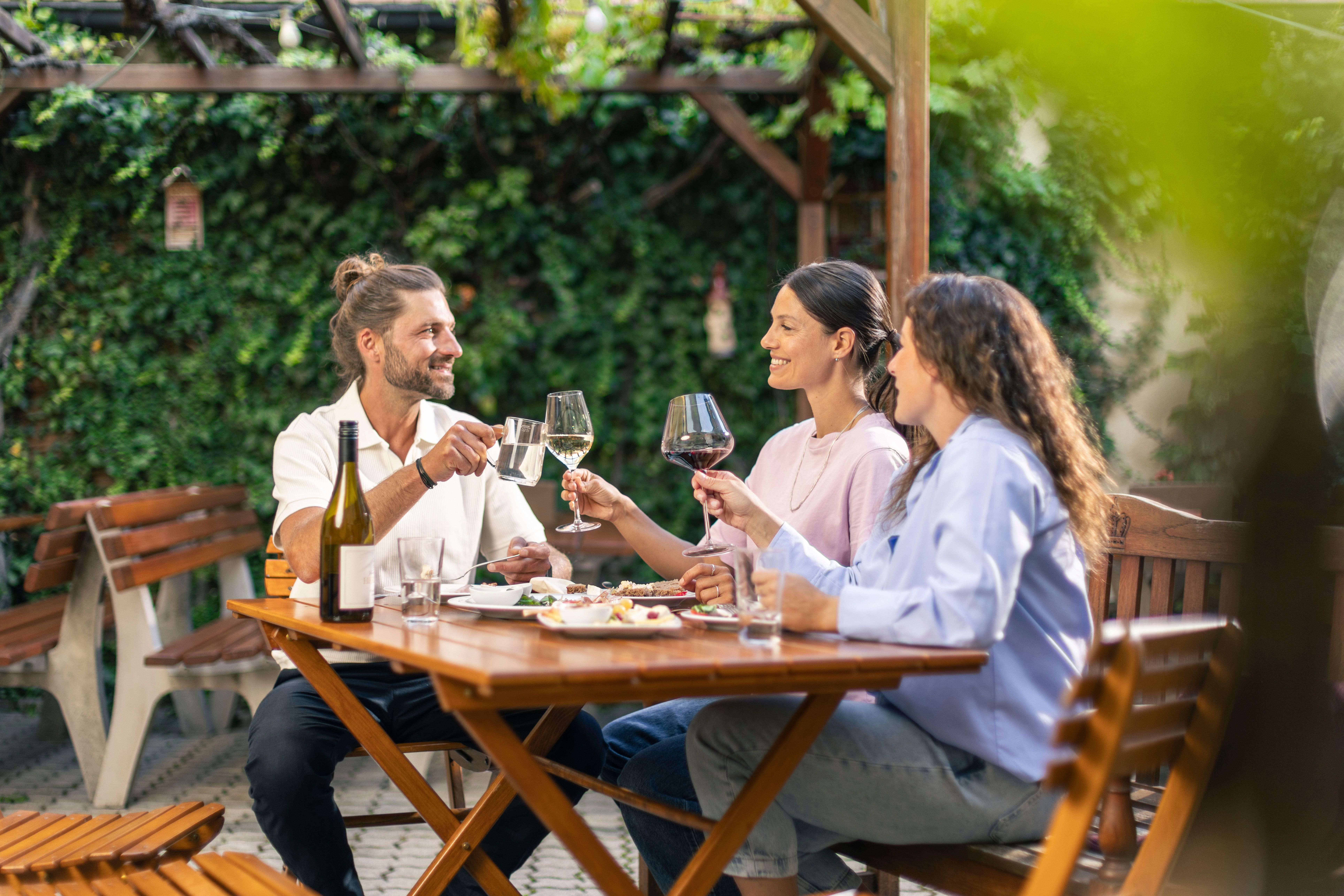 In der kühlen Abenddämmerung erstrahlt der Innenhof des Weinguts in warmem Licht. Gemütliche Sitzgelegenheiten laden dazu ein, die frische Luft und die ruhige Atmosphäre zu genießen, während der Duft von Wein und regionalen Köstlichkeiten in der Luft liegt.