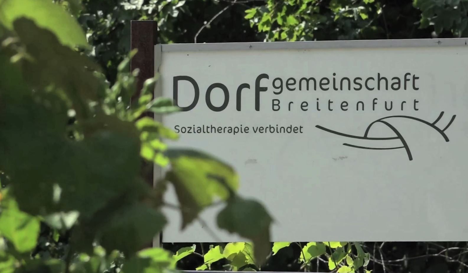 Schild der Dorfgemeinschaft Breitenfurt mit dem Slogan 'Sozialtherapie verbindet'.