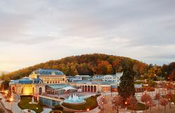 Die sanften Hügel des Wienerwaldes umarmen das elegante Casino, während die bunten Blätter der Bäume im sanften Licht der Abenddämmerung leuchten. Ein Ort, der zum Verweilen einlädt und die Seele mit seiner malerischen Schönheit berührt.