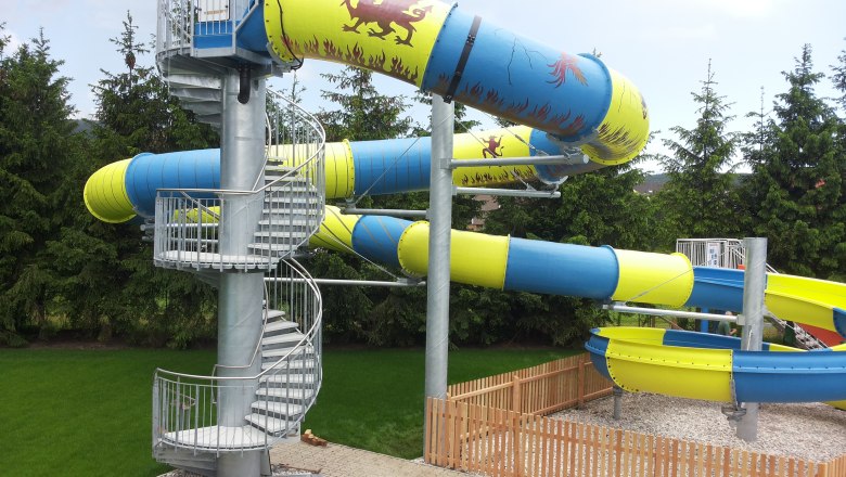 Large water slide with blue and yellow tubes and spiral staircase.