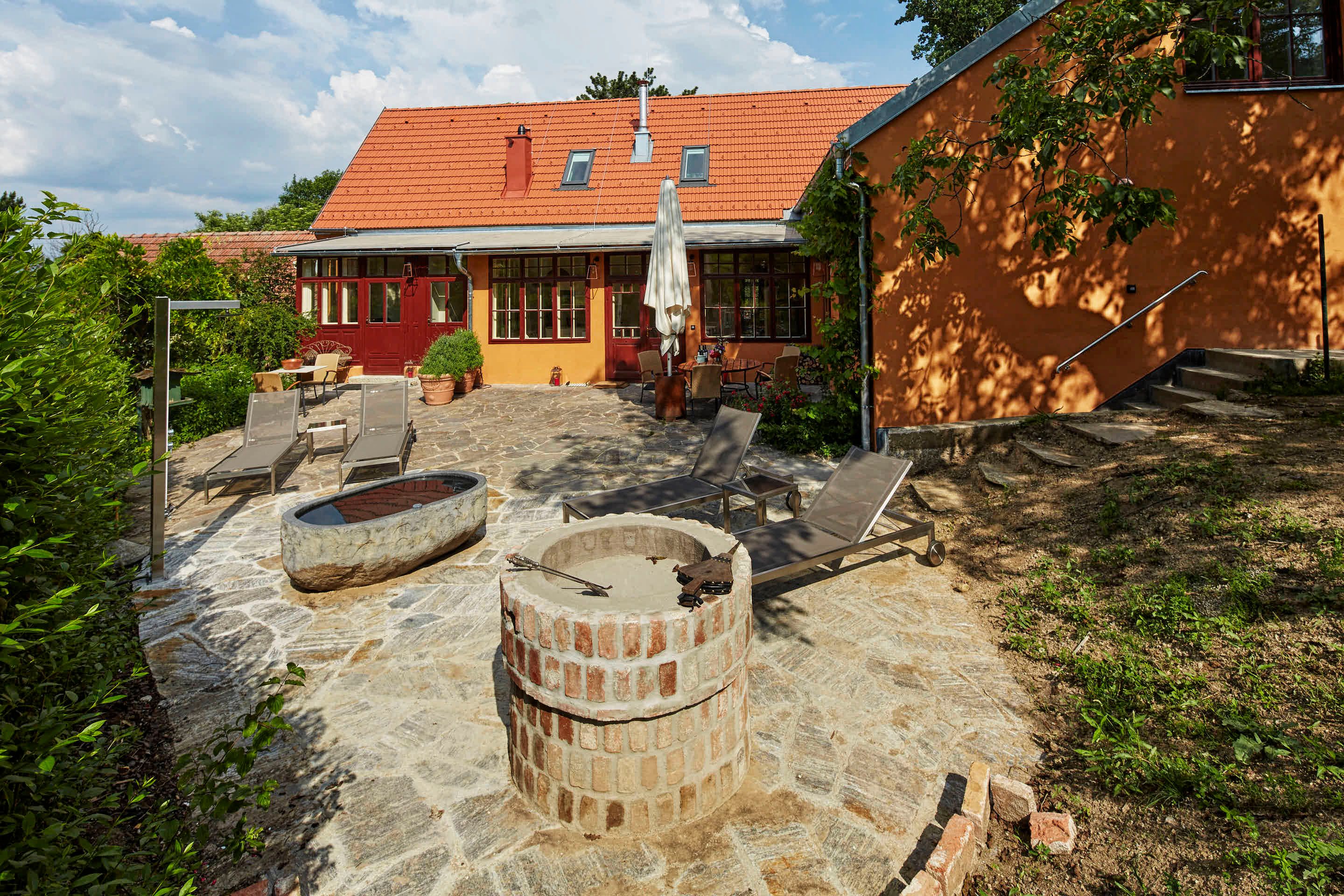 Terrasse einer Villa mit Liegestühlen und Feuerstelle.