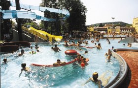 Menschen im Freizeitzentrum Mödling im Schwimmbecken mit Rutschen.