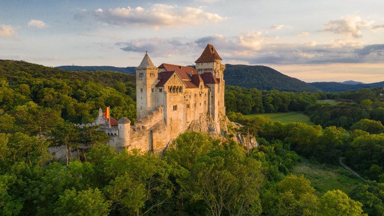 Burg Liechtenstein inmitten grüner Wälder bei Sonnenuntergang.