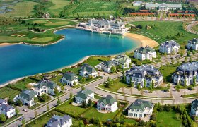 Luftaufnahme von Oberwaltersdorf mit einem See, umgeben von Villen und einem Golfplatz.