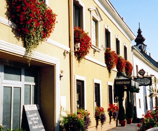 Ein traditionelles Gasthaus mit gelber Fassade und roten Blumen an den Fenstern.