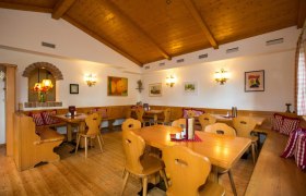 Gemütliche Stube mit Holzmöbeln, karierten Kissen und Wanddekorationen.