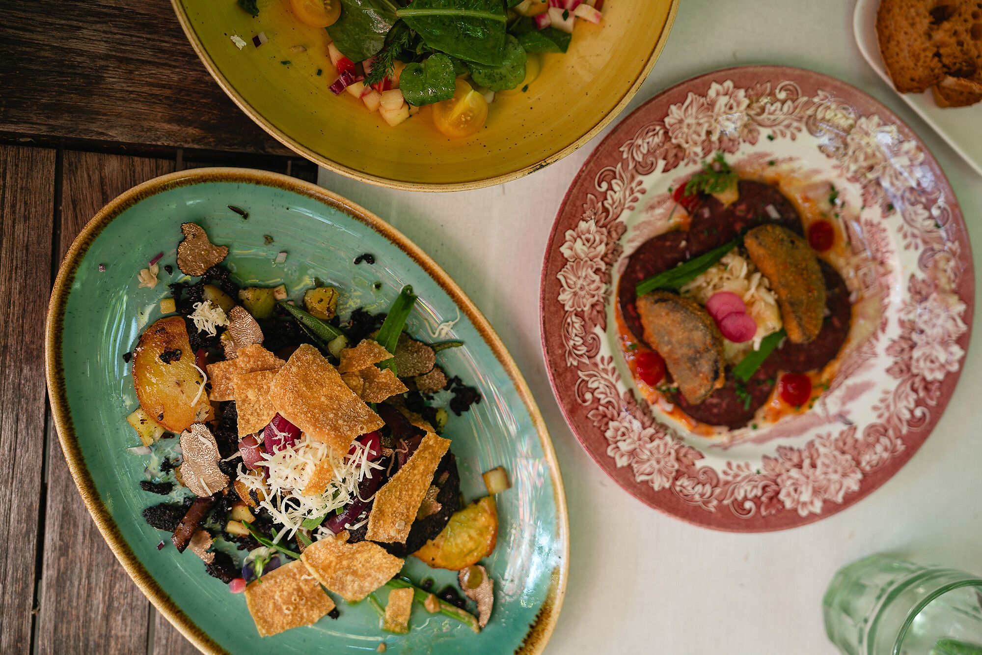 Ein liebevoll arrangiertes Stillleben mit frischen Bio-Gemüsen, Kräutern und weiteren Slow-Food-Produkten auf einem rustikalem Holztisch.