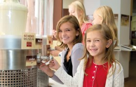 Kinder im Schokomuseum bedienen einen Schokoladenspender.