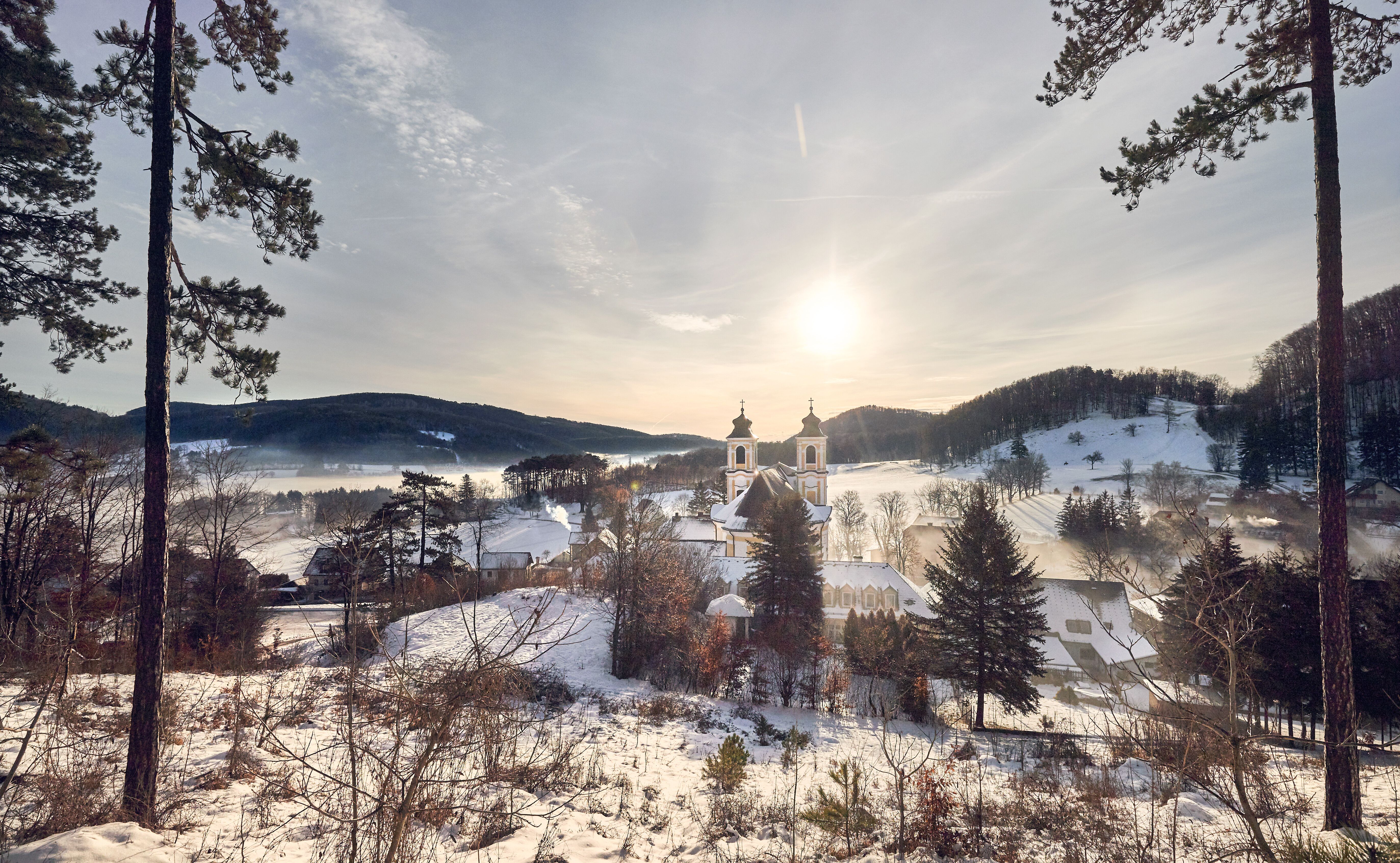 In der winterlichen Landschaft des Wienerwaldes strahlt die Sonne über schneebedeckten Hügeln und verleiht der Szenerie eine magische Atmosphäre. Die sanften Konturen der Bäume und die ruhige Stille der Natur laden zu einem besinnlichen Spaziergang ein. Hier, wo die Zeit stillzustehen scheint, entfaltet sich die Schönheit des Winters in voller Pracht.