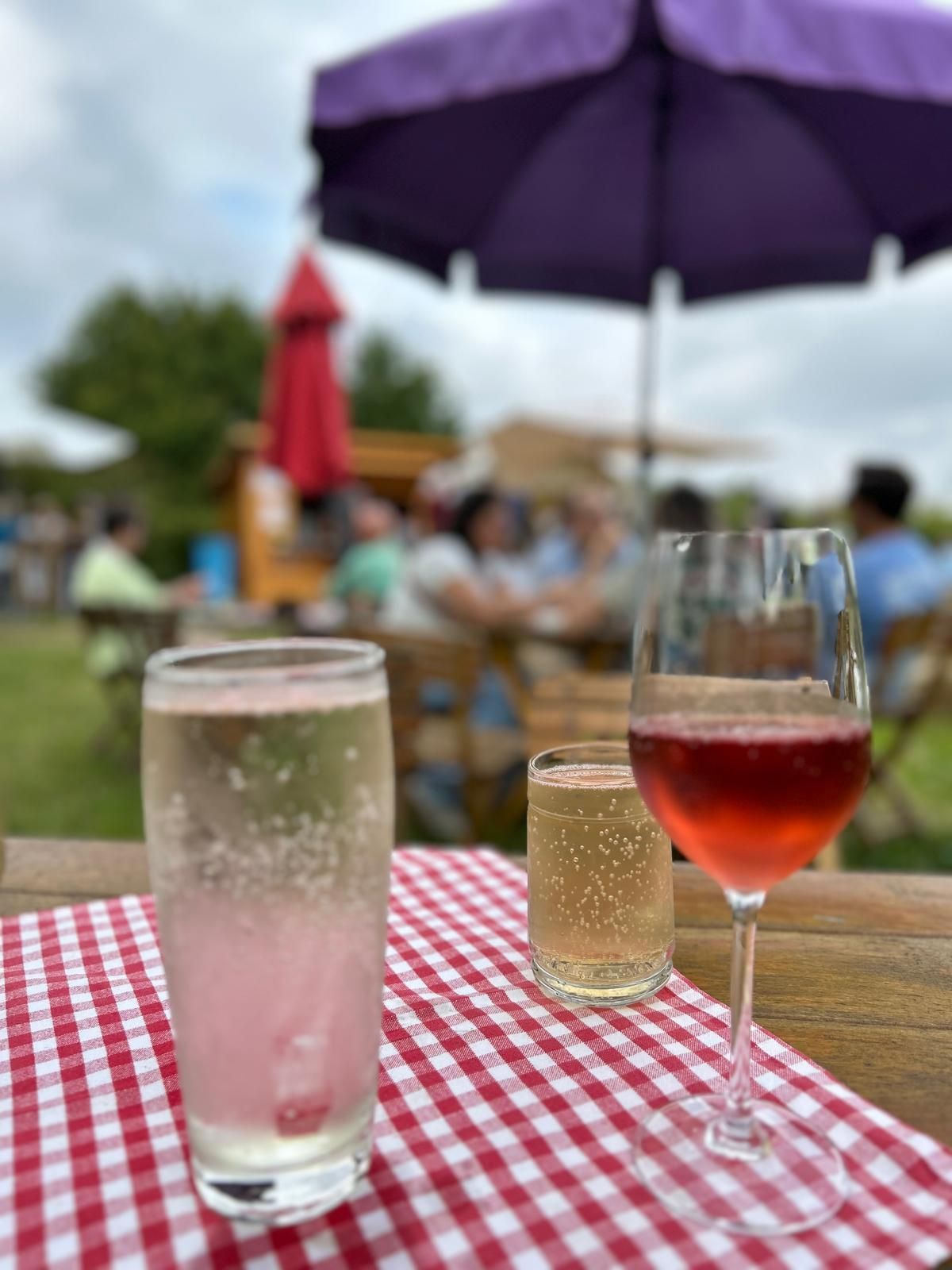 Gespritzte alkoholfreie Getränke und Weißwein Spritzer sowie Wein-Bowle auf einem rot weiß karierten Tischtuch auf einem Heurigentisch entlang der Genussmeile.