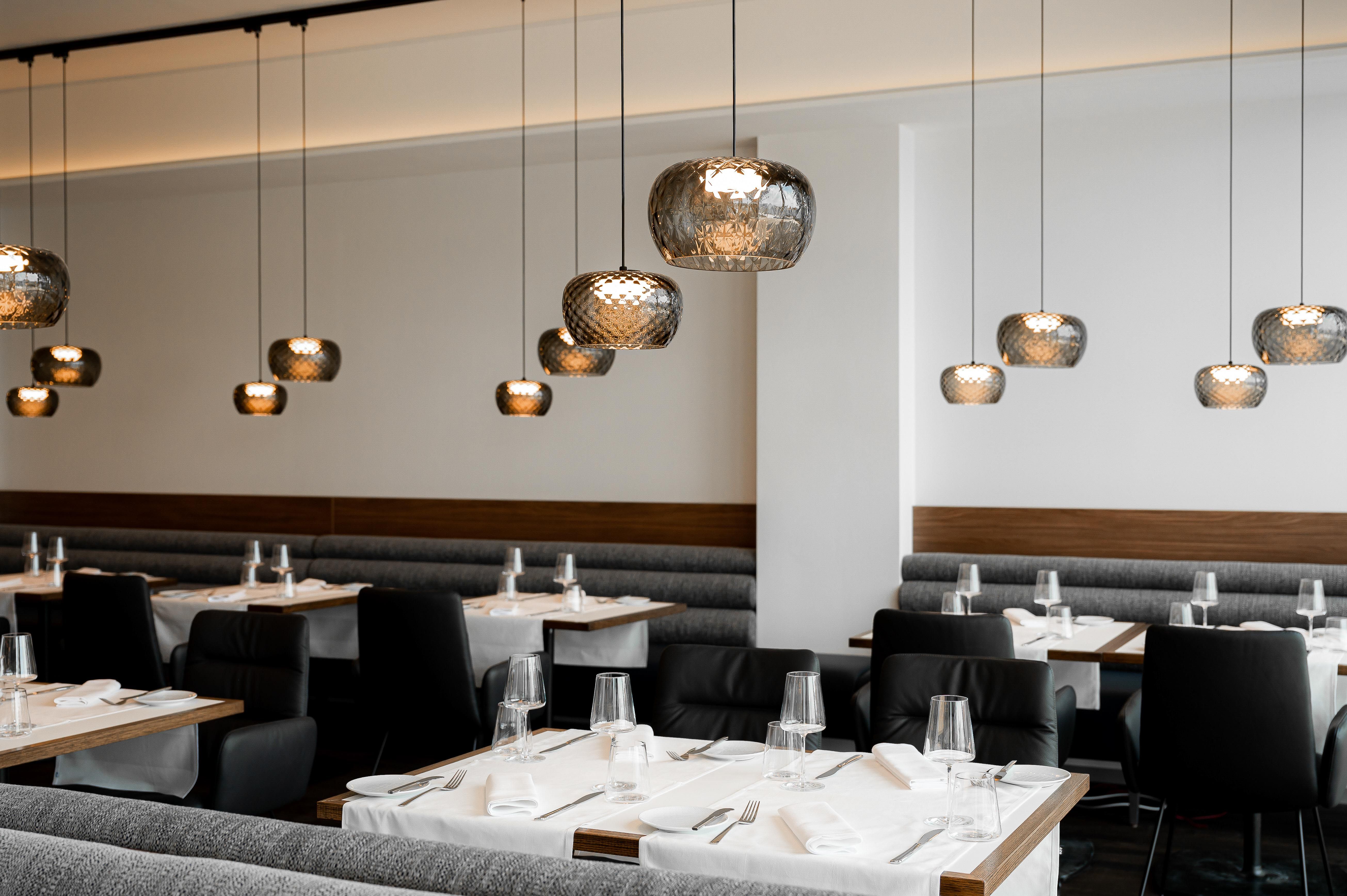 Modernes Restaurant mit eleganten Hängelampen und gedeckten Tischen.