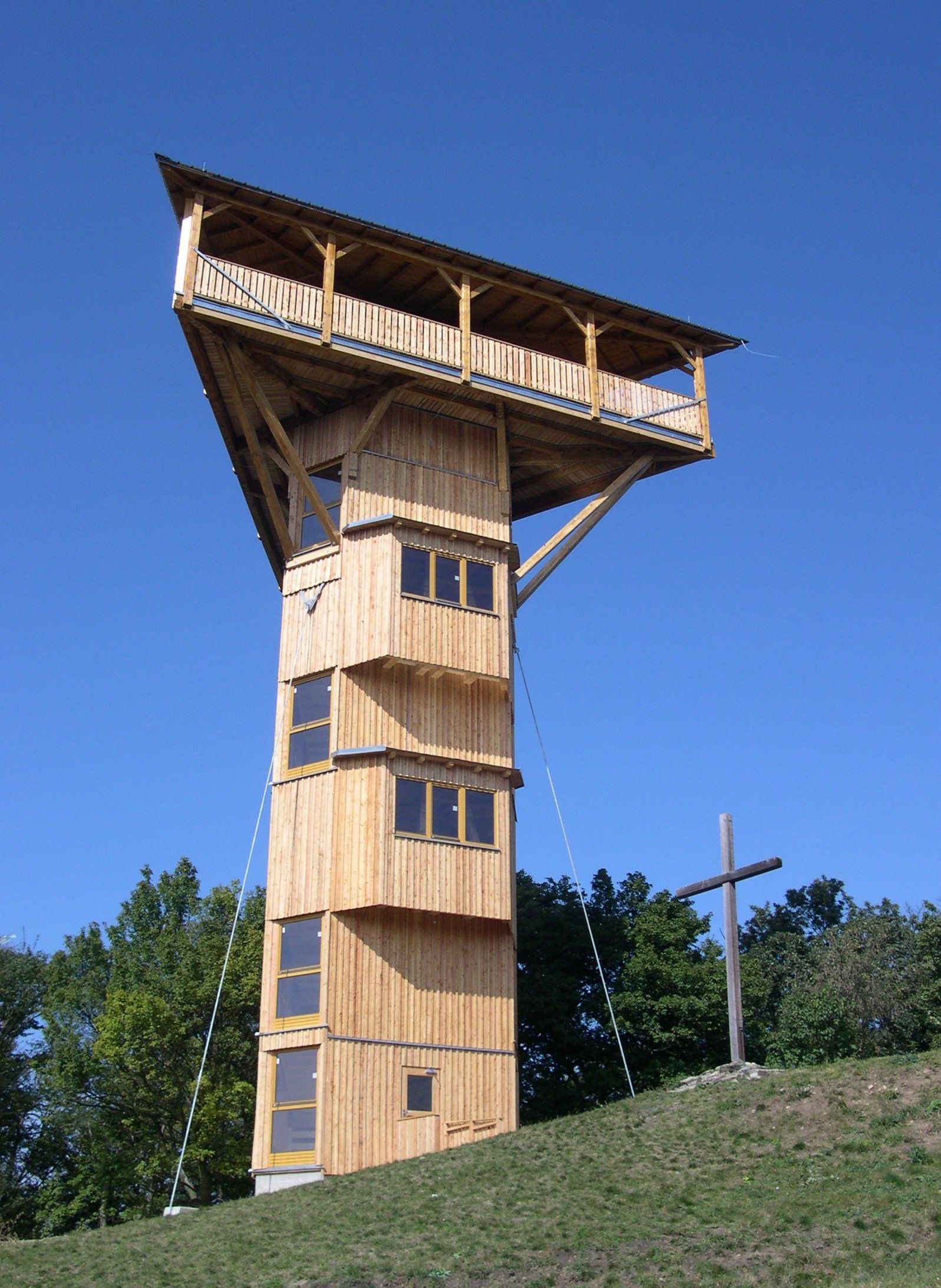 Holzturm Buchbergwarte mit Kreuz daneben, blauer Himmel.